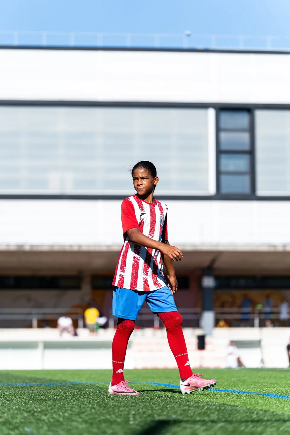 Young player in a red and white striped shirt on the pitch