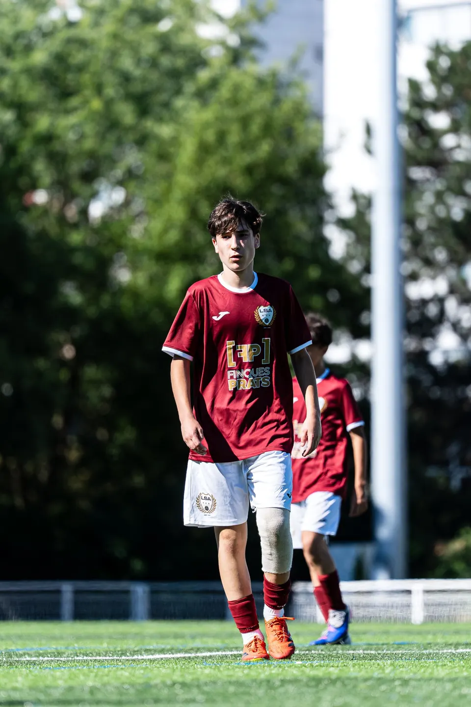 Young player in a maroon shirt on the pitch